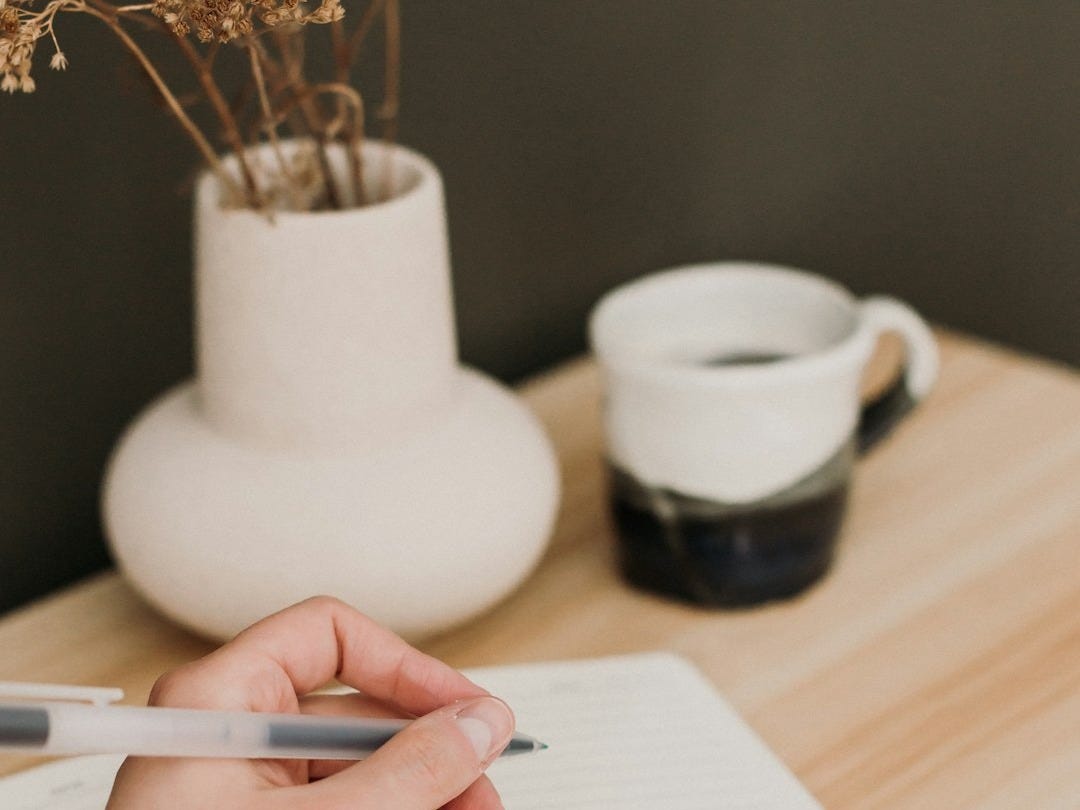 a person writing on a notebook with a pen