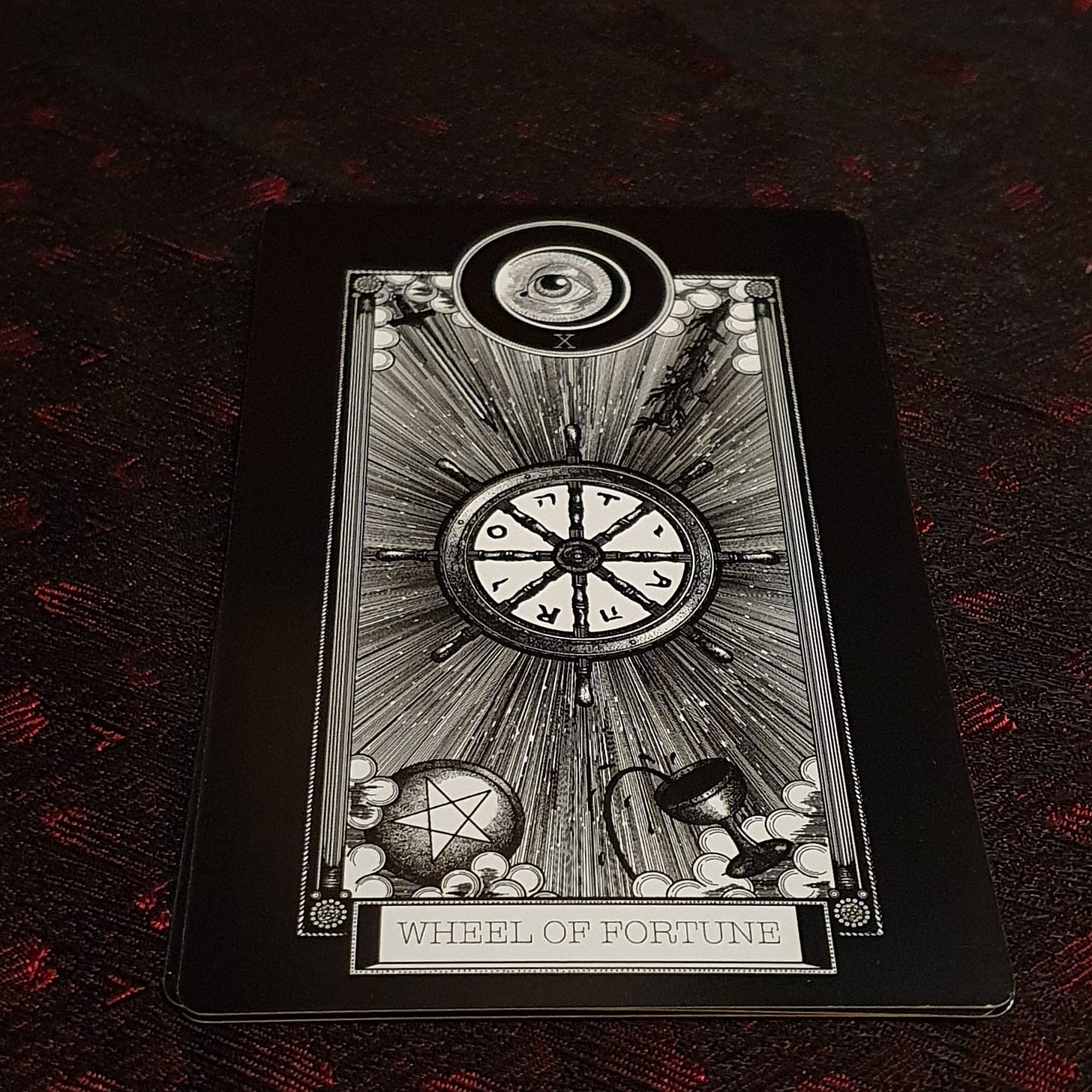The Wheel of Fortune card sits on red and black silk The Wheel of Fortune card sits on red and black silk