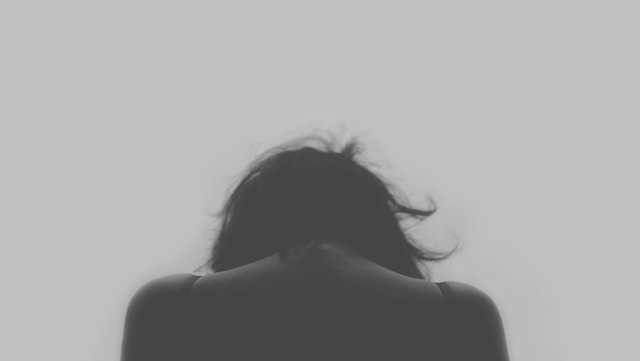 Woman facing away, head down, symbolising feelings of loneliness and emotional struggle.