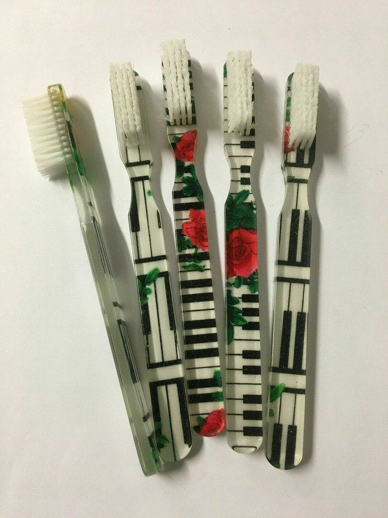 May include: Five toothbrushes with white bristles and different designs. Four toothbrushes have a black and white piano key design with red roses. One toothbrush has a floral design with red roses. May include: Five toothbrushes with white bristles and different designs. Four toothbrushes have a black and white piano key design with red roses. One toothbrush has a floral design with red roses.
