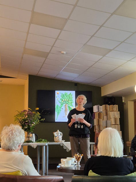 There are three images on the top, and two below. 1.	Activity workshop space inspired by the library’s natural environment and history. Photo by A. Petreike The environment was designed in reference to the library’s natural surroundings and historical background, reflecting the plant-themed concept of the workshop.  2.	Educational postcard with plant motif. Photo by A. Petreike Participant holding a plant-themed educational postcard, developed as part of the educational materials. The postcards invited participants to recognize familiar plants, color them and take them home to take home as a meaningful keepsake of the activity workshop. The back of the postcard featured the library contact person and their details, offering a way to connect.  3.	Educator interacting with participants. Photo by A. Petreike The educator engages participants by explaining and discussing different plants, fostering curiosity and sensory exploration (using a screen to show images, offering herbal tea to explore flavors, presenting postcards).  4.	Virtual reality experience. Photo by U. Padagiene Participant explores the library’s orangery using virtual reality glasses while the educator observes and guides the experience, enhancing engagement and sensory learning.  5.	Activity workshop session. Photo by A. Petreike