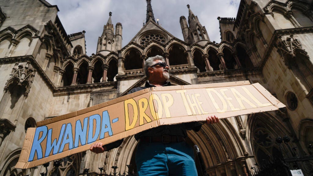 An activist in the United Kingdom holds a banner during a protest against the British government's failed plan to deport asylum seekers to Rwanda.
