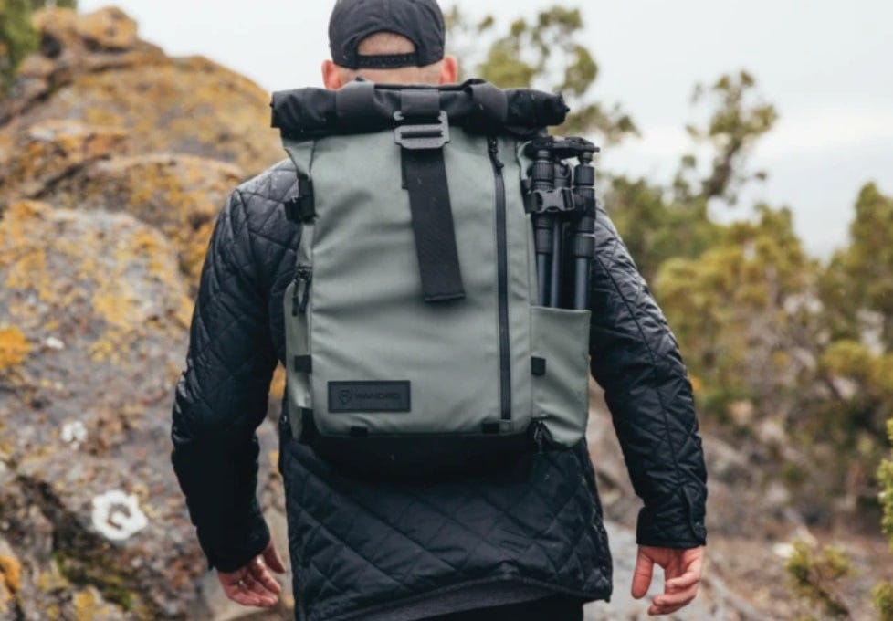 a man wearing the PRVKE pack hikes up a hill to take an epic picture at the top a man wearing the PRVKE pack hikes up a hill to take an epic picture at the top