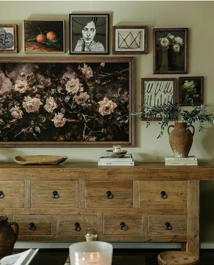 This may contain: a living room with pictures on the wall and flowers in vases next to an old dresser