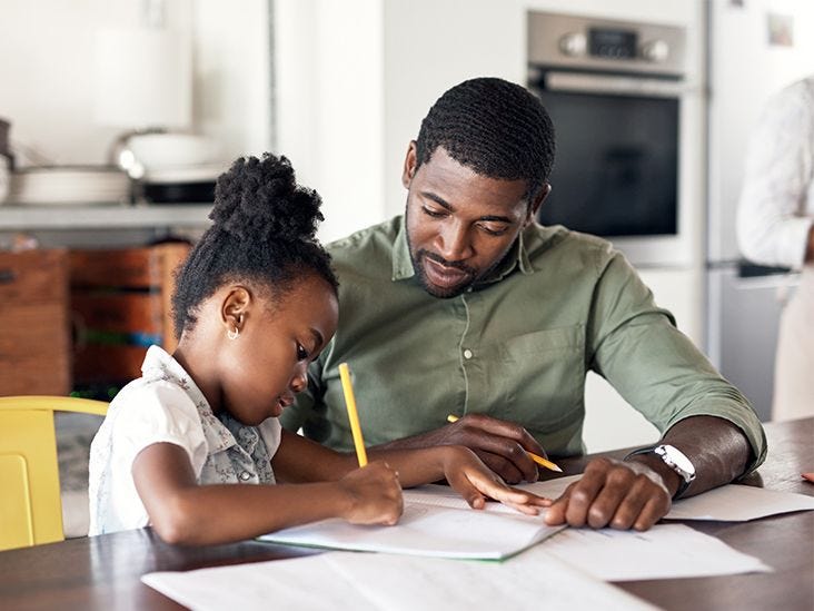 This may contain: a father and daughter doing homework in the kitchen