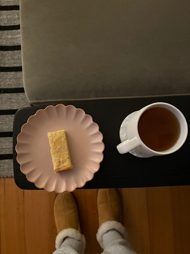 Cinnamon roll focaccia for sale at a cafe and a slab of lemon shortbread with peppermint tea beside a couch