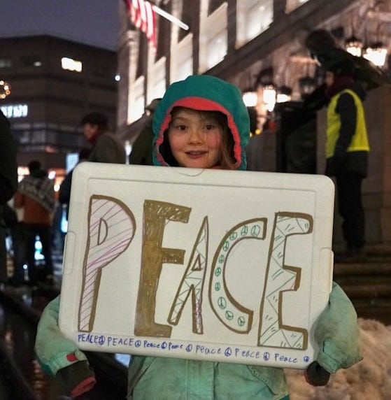 a little girl holding a sign that says peace