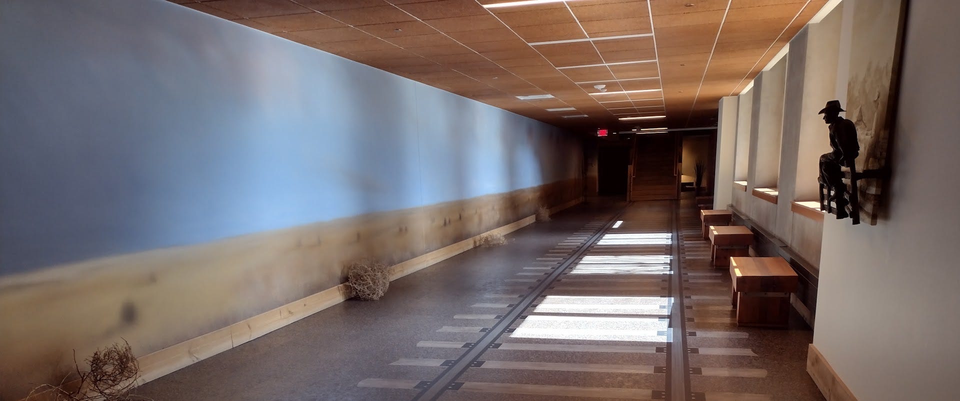 Long hallway with train track painted on floor and actual tumbleweeds against wall Long hallway with train track painted on floor and actual tumbleweeds against wall