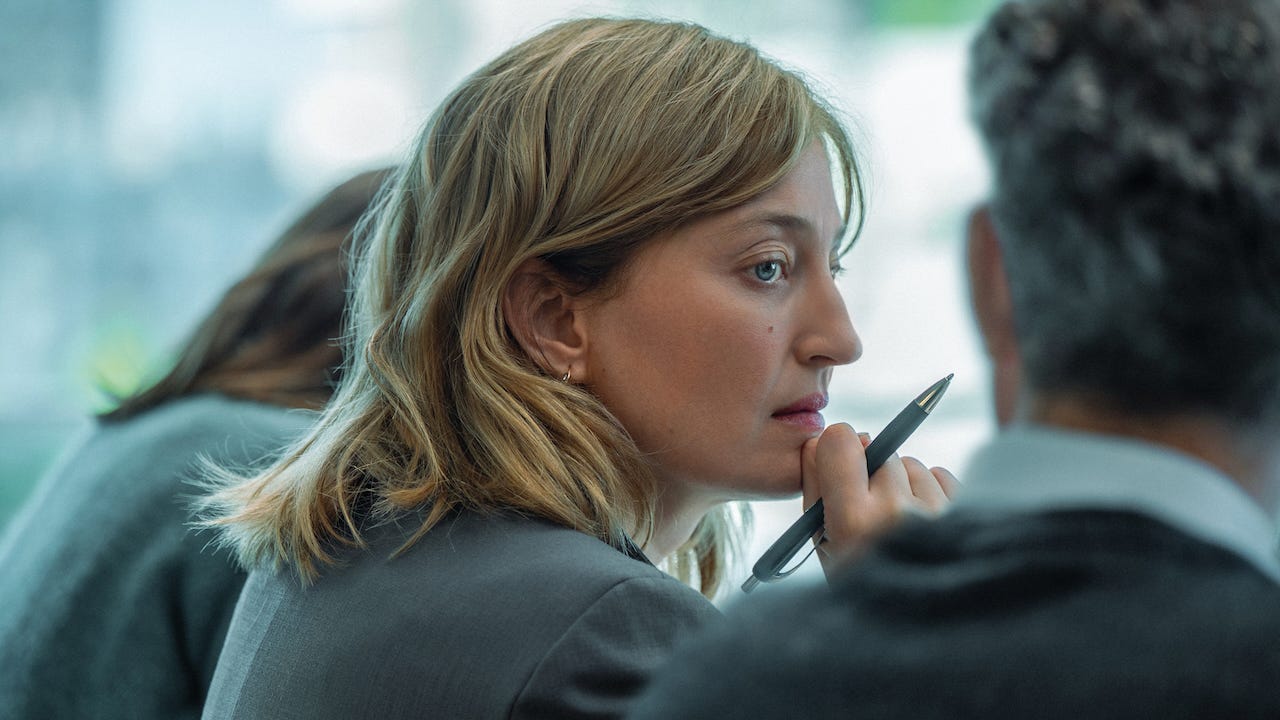 Alba Rohrwacher with pen in hand sitting at desk during a board meeting in the movie A Good Little Soldier Alba Rohrwacher with pen in hand sitting at desk during a board meeting in the movie A Good Little Soldier