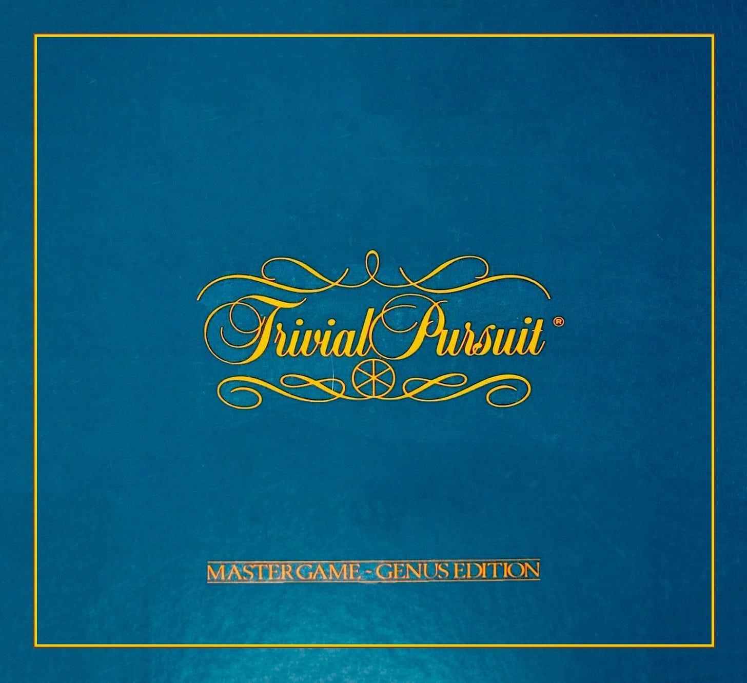 The iconic Trivial Pursuit Box, plain blue with its name and the six-wedge centerpiece.