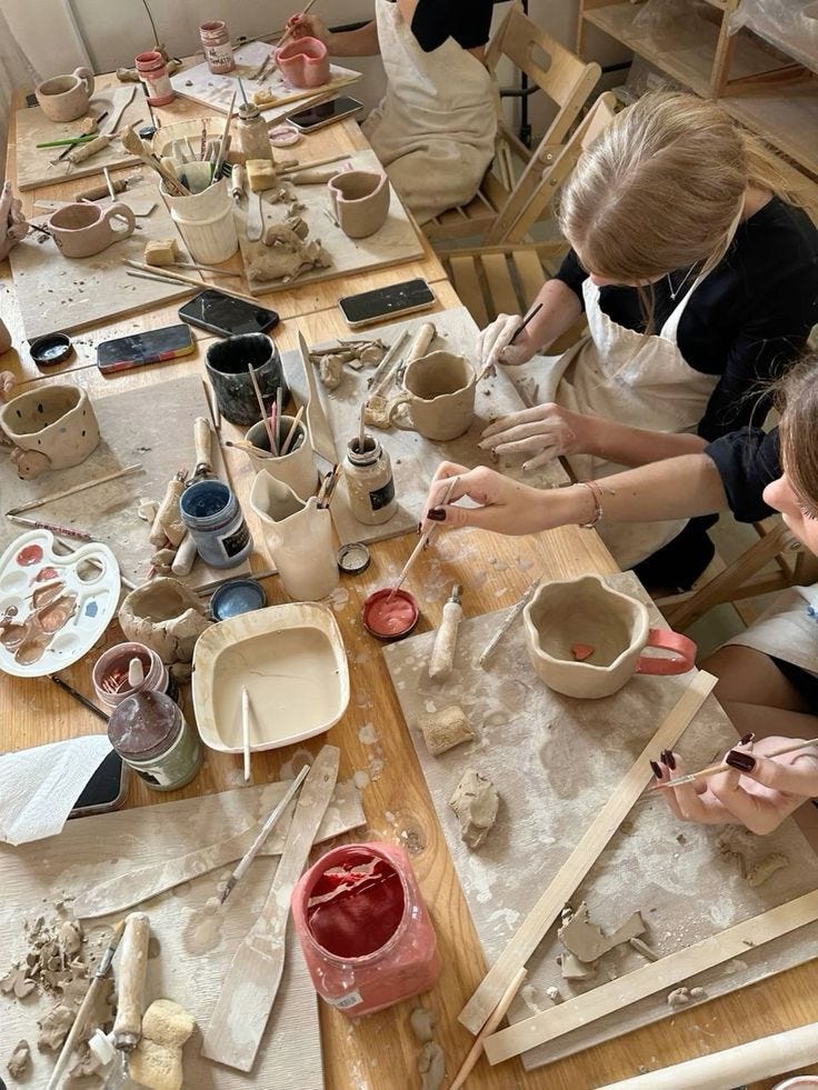 This may contain: two women working on pottery at a table