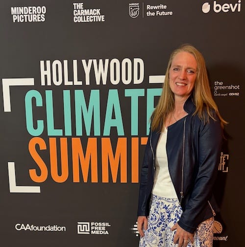 Julie Carrick Dalton standing in front of a promotional banner reading Hollywood Climate Summit.