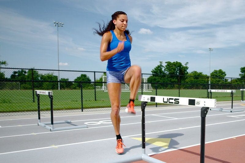 Female track athlete doing a hurdle-specific warm-up.