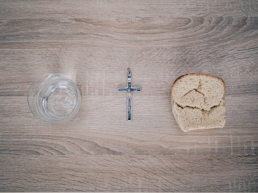 closeup photo of silver-colored cross pendant beside baked bread closeup photo of silver-colored cross pendant beside baked bread