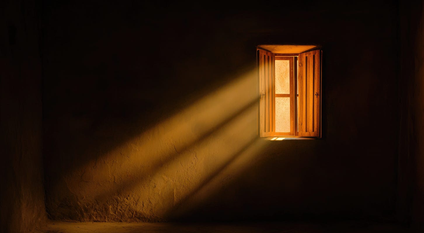 A dark, empty room with a small wooden window partly open, letting in a warm strip of sunlight that stretches across the textured wall.