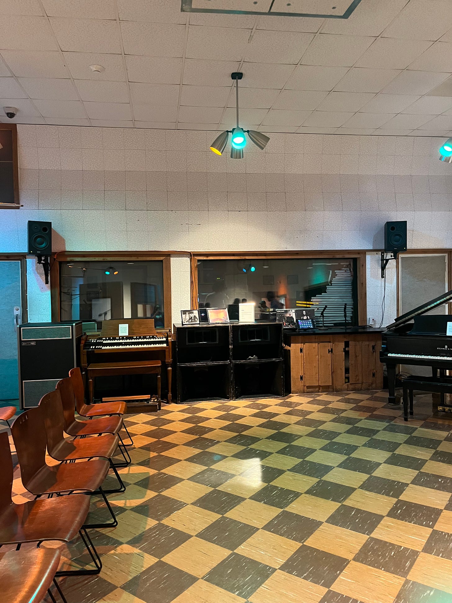 The inside of RCA Studio B, showing the checkered linoleum floor, the control room, chairs set up for where people come in to tour, the colored mood lights, etc.
