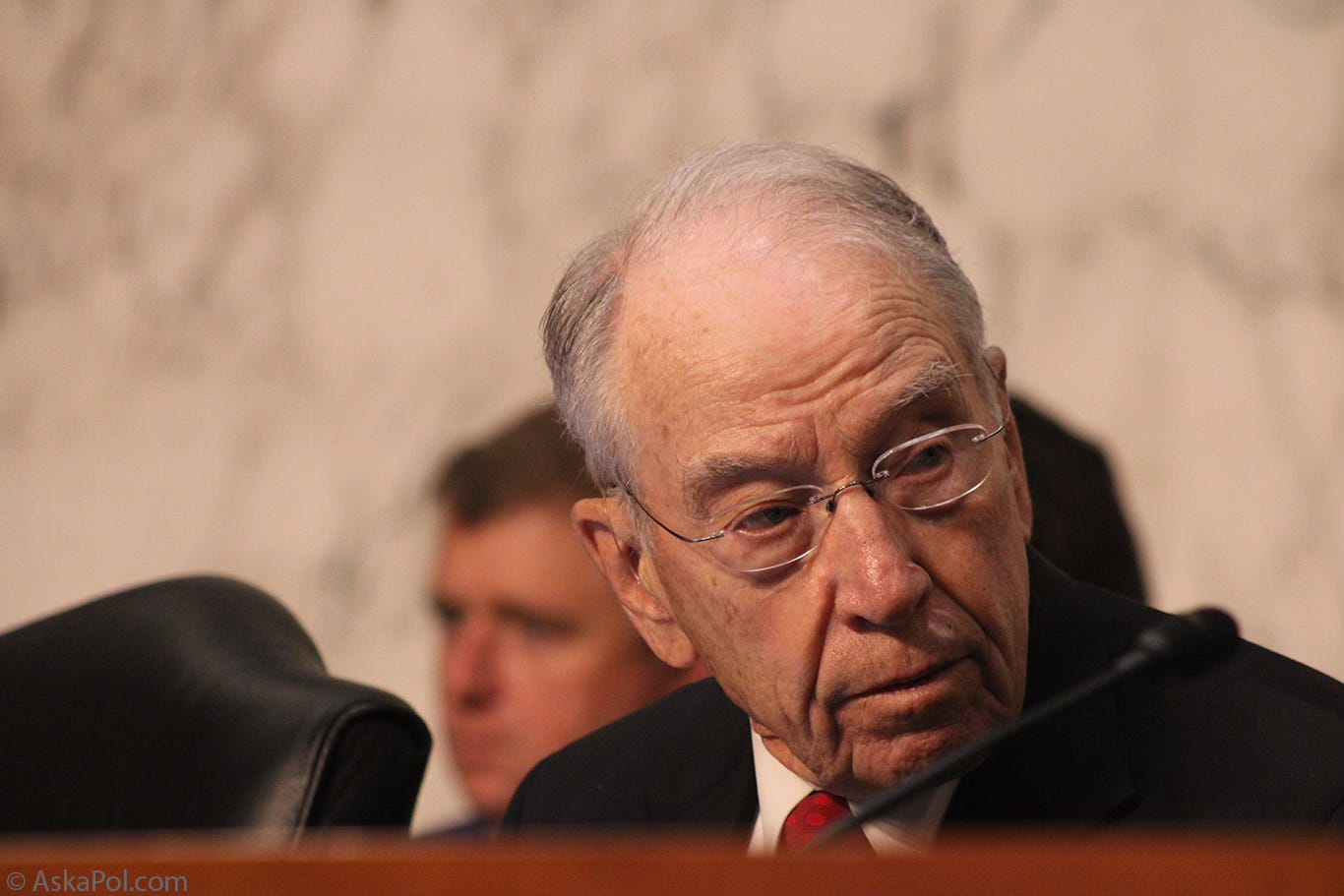 Elderly man in red tie turns head to listen Photo: Logan Johnson © www.askapolpolitics.com