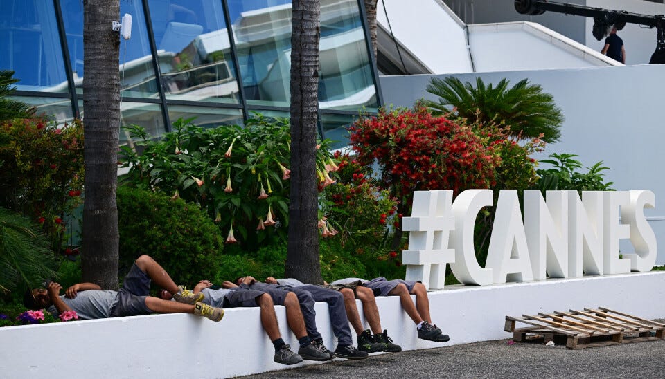 Workers rest next to a Cannes sign on the sidelines of the 79th edition of the Cannes Film Festival in Cannes, southern France, on May 11, 2026.