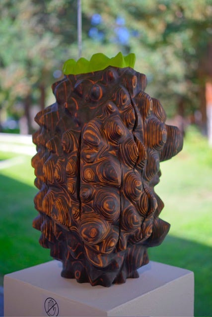 Small sculptural form in partially charred redwood with oil paint, carved into a compact vertical shape with repeating rounded ridges and visible wood grain. Small sculptural form in partially charred redwood with oil paint, carved into a compact vertical shape with repeating rounded ridges and visible wood grain.