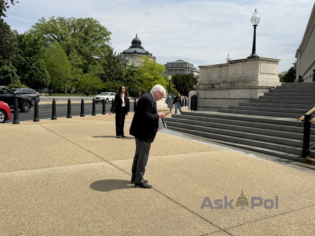 Man with gray hair and in sportcoat stops on sidewalk to check his phone on sunny day. Photo: Matt Laslo © www.askapoluaps.com 