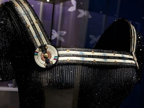 Midnight-blue velvet gown and black corseted dress with porcupine-quill neckline by Gucci and Joe Big Mountain of Ironhorse Quillwork. Worn by Lily Gladstone to the Oscars when she was nominated for Best Actress for Killers of the Flower Moon.