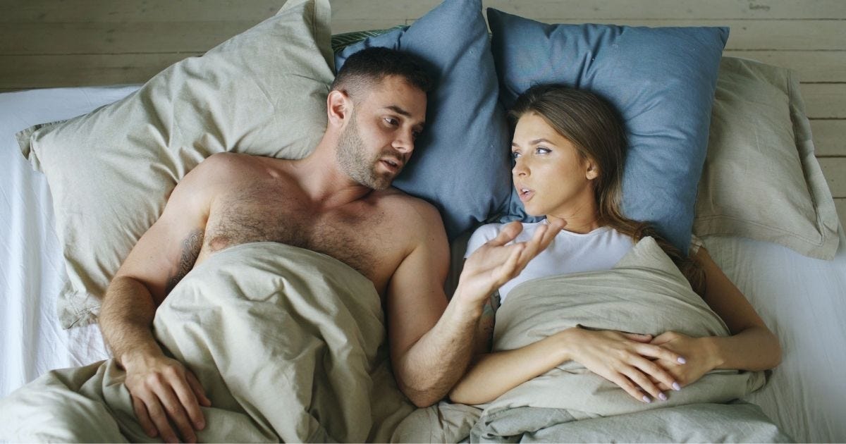 Couple lying in bed under blankets, engaged in conversation Couple lying in bed under blankets, engaged in conversation