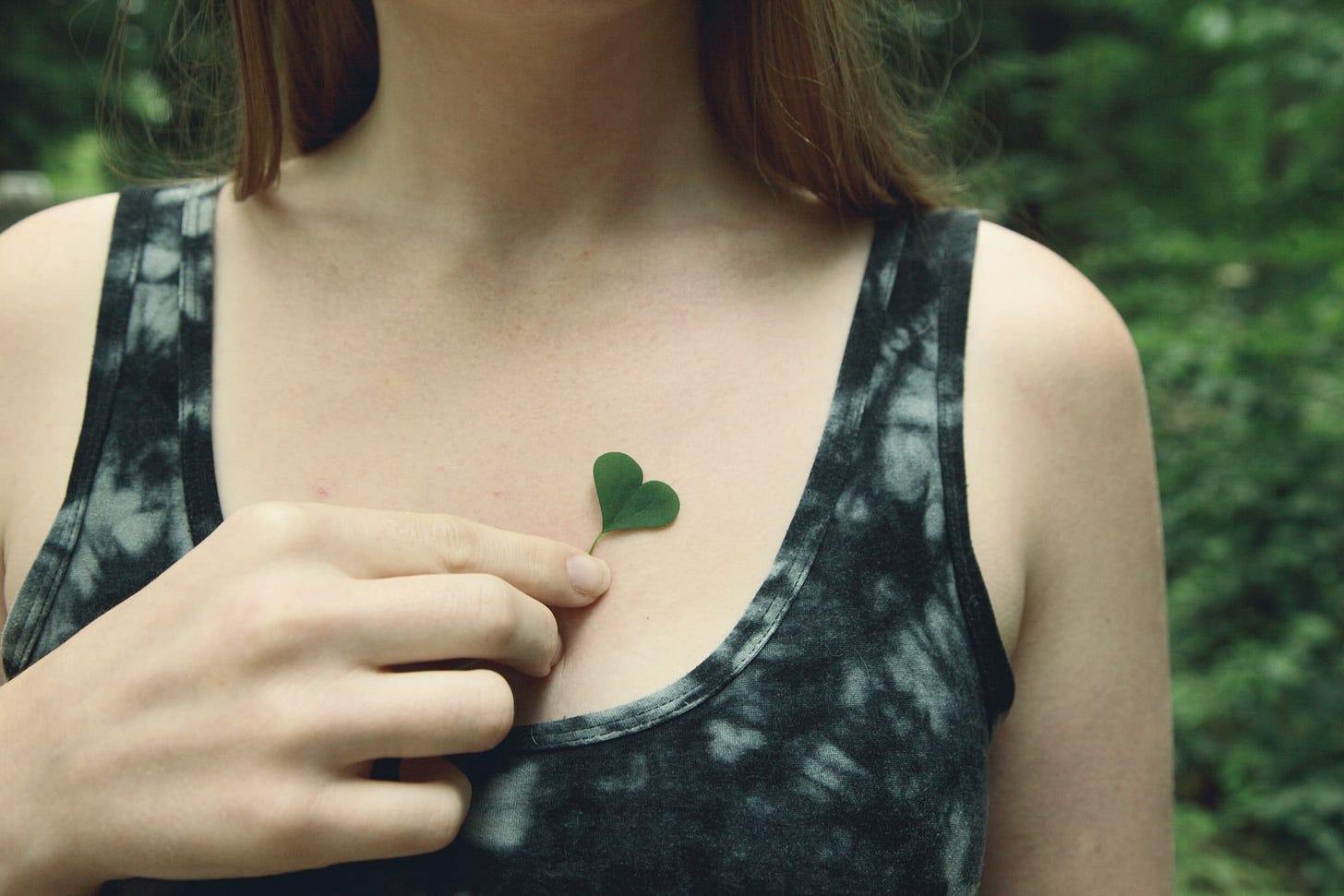 Woman holding a heart-shaped clover over her heart