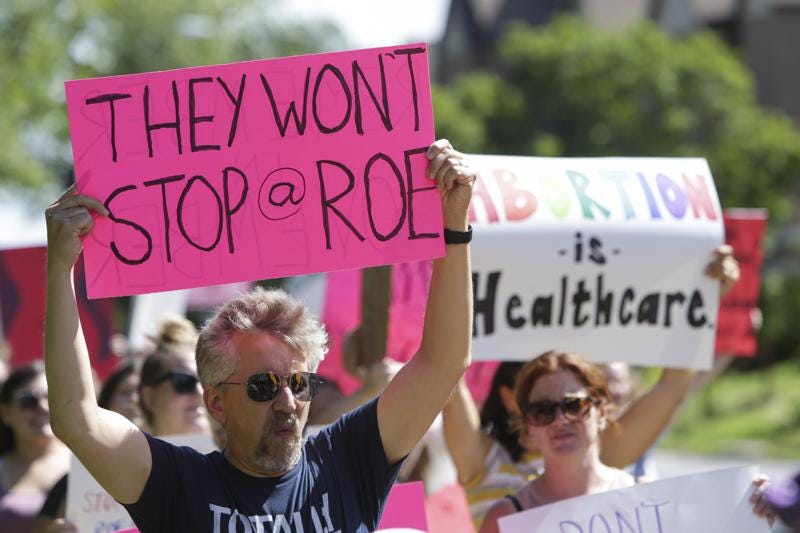 FILE - A man holds a sign as community members walk around Vander Veer Park during a march following the Supreme Court decision to overturn Roe v. Wade, June 26, 2022, in Davenport, Iowa. Democrats and their aligned groups raised more than $80 million in the week after the Supreme Court stripped away a woman’s constitutional right to have an abortion. The flood of cash offers one of the first tangible signs of how the ruling may energize voters. (Nikos Frazier/Quad City Times via AP)