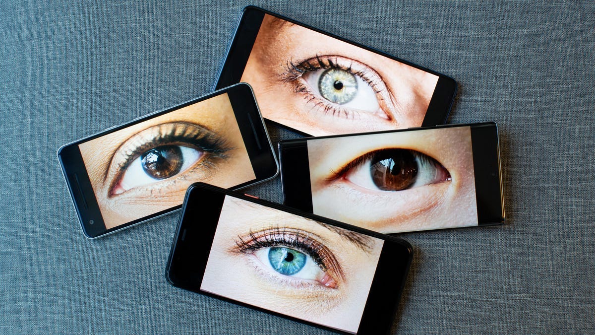 Four smartphones, each with an eyeball staring at you Four smartphones, each with an eyeball staring at you