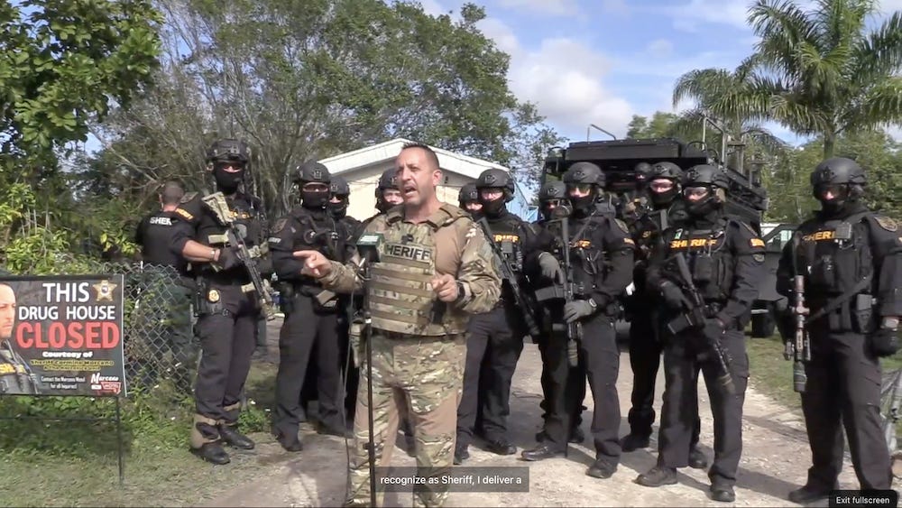 r/policeporn - Lee County, FL Sheriff Carmine Marceno gives a press conference surrounded by his deputies in full SWAT drip [1000x563]