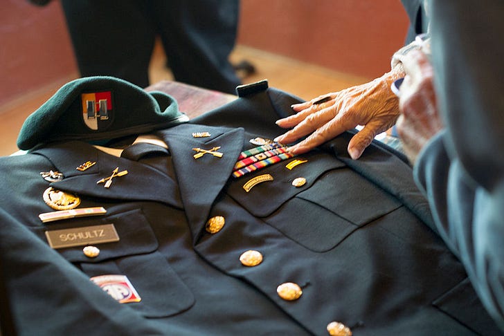 A woman reaches to touch the ribbons of Army Special Forces Capt. Joseph Schultzs' uniform, following memorial services on June 11, 2011. (Photo by Ken Cedeno/Corbis via Getty Images)
