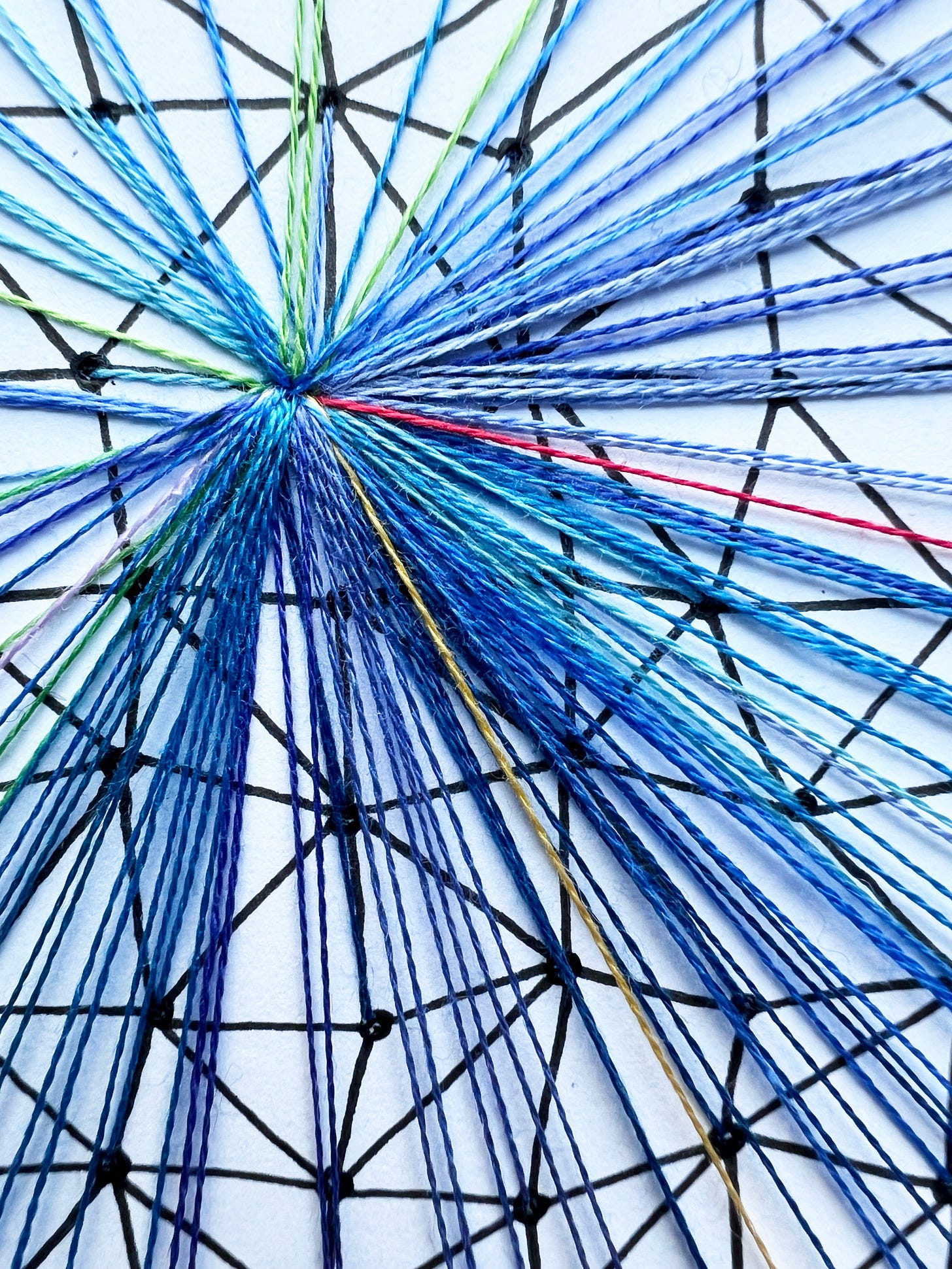 Close-up image of colourful threads converging into a central knot. The threads are blue, green, red, and yellow, stitched onto a geometric black grid. The central knot represents the small area of conscious awareness amid overwhelming sensory input.
