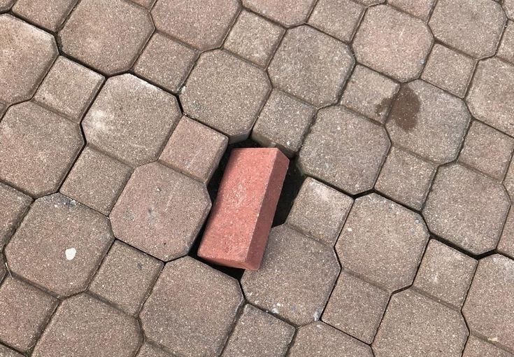 This may contain: a brick laying on the ground with words above it