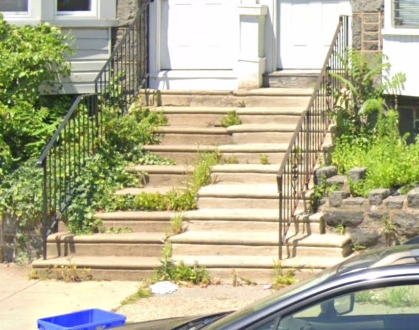 A photo of two West Philly homes' entryways, with at least 8 steps leading up to the door.