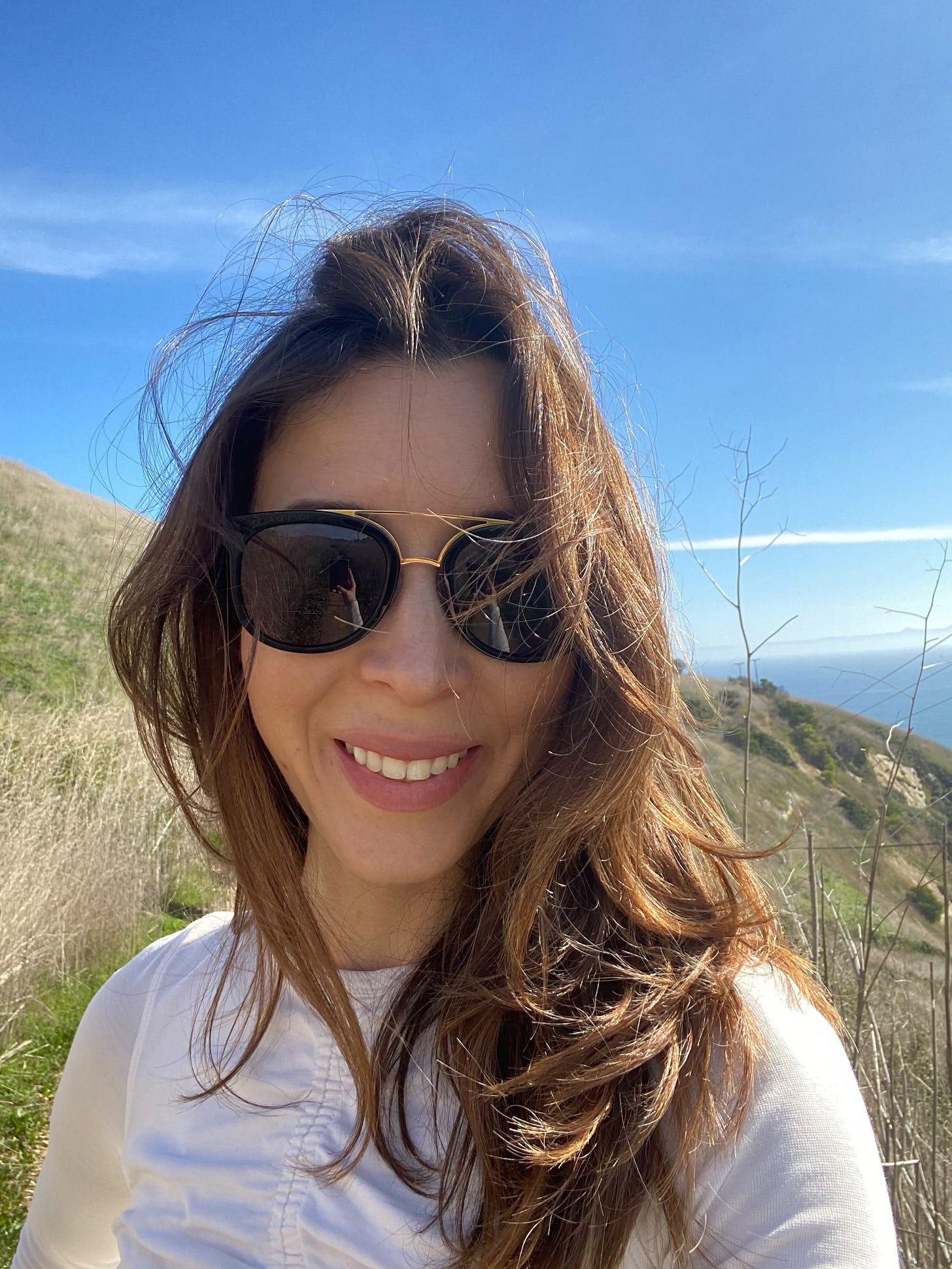 Zazie Peltier smiling outdoors on a coastal hillside, photo accompanying a Human Design and career pivot feature on Status CWO Zazie Peltier smiling outdoors on a coastal hillside, photo accompanying a Human Design and career pivot feature on Status CWO