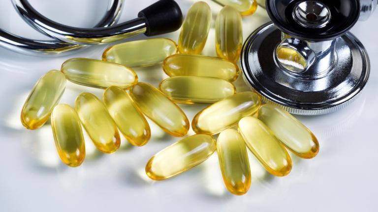 A handful of semi transparent yellow gel capsules are laid out on a counter. A stethoscope is nearby.