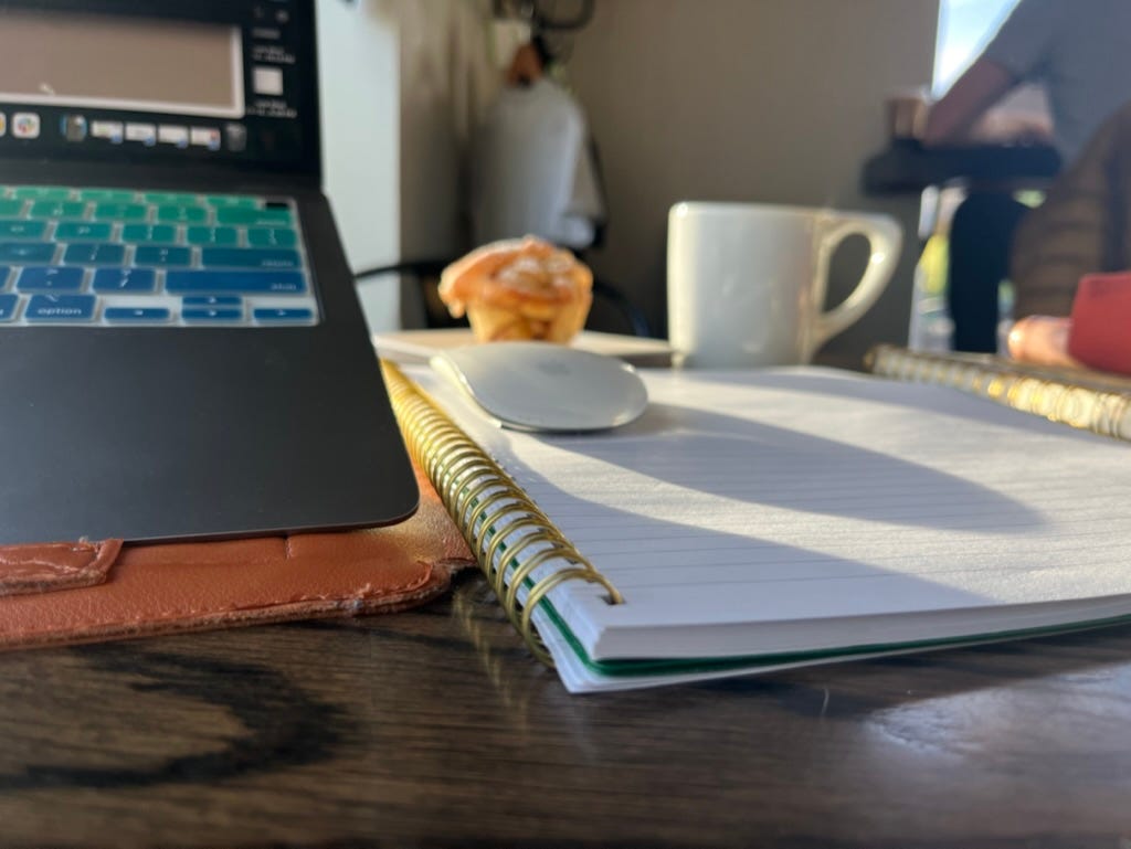 Photo of a notebook and laptop at a coffee shop Photo of a notebook and laptop at a coffee shop