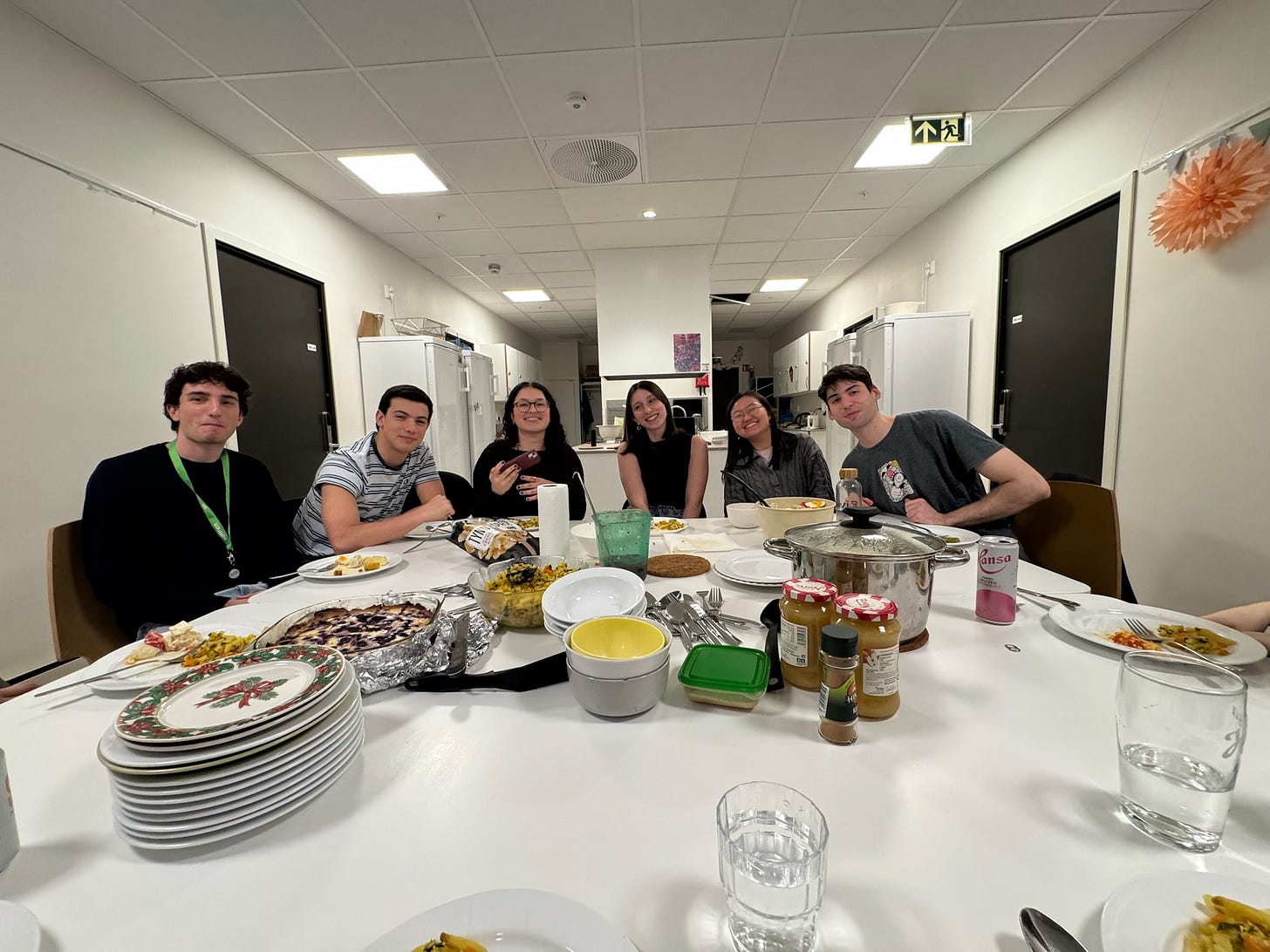 6 friends sit pleasantly eating dinner together