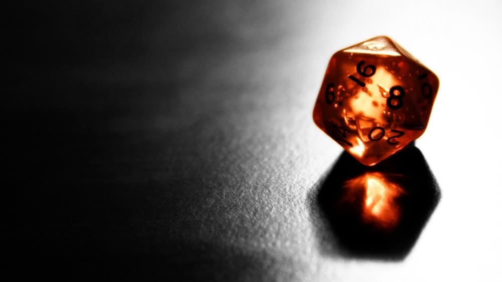 An amber-colored d20 on a shiny gray surface An amber-colored d20 on a shiny gray surface