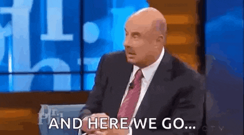 a bald man in a suit and tie is sitting on a stage and talking on a television show .