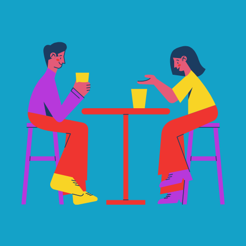 Two people wearing purple and sat at a table having a drink together Two people wearing purple and sat at a table having a drink together