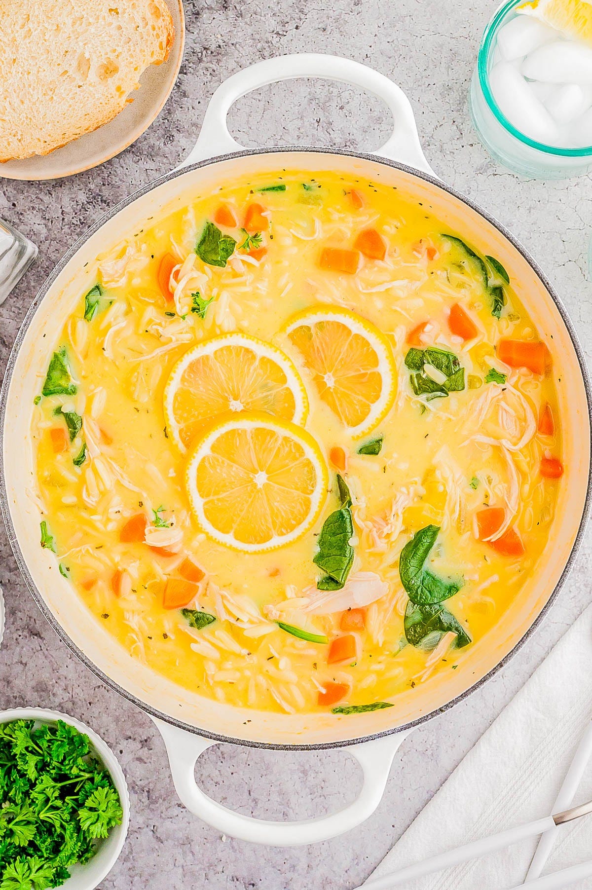 A pot of lemon chicken soup topped with three lemon slices. A pot of lemon chicken soup topped with three lemon slices.