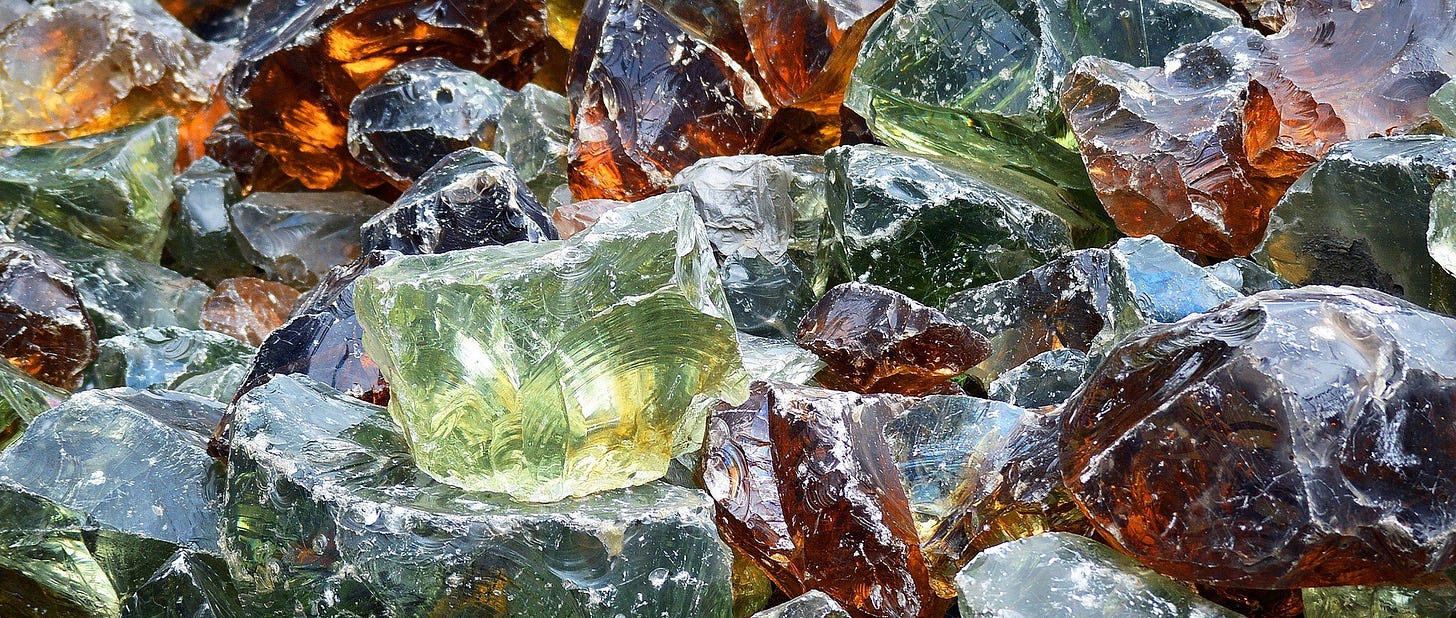 A pile of uneven chunks of broken glass in a variety of colors.