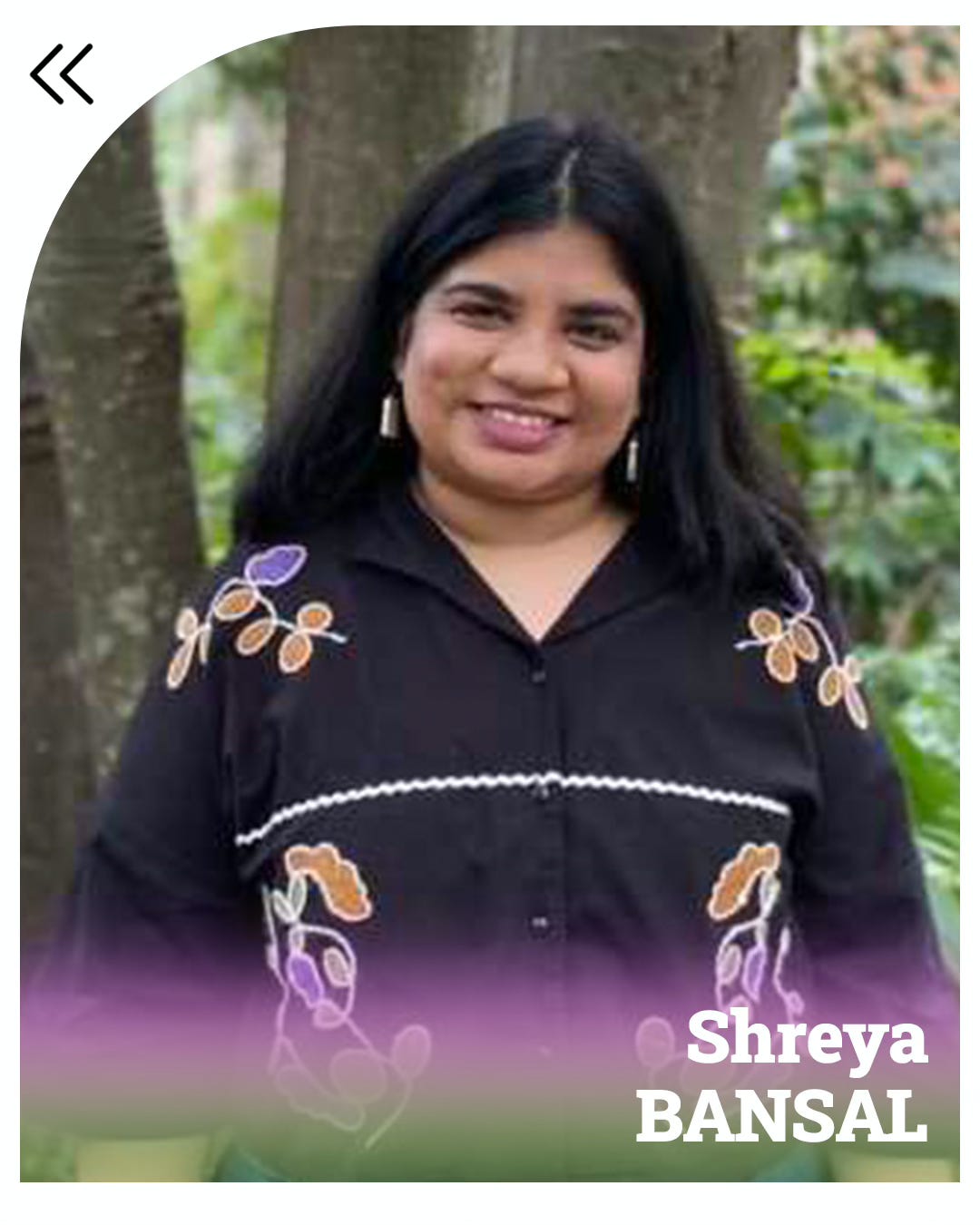 Shreya, an Indian woman with shoulder-length black hair, is standing in a forest with greenery around her. She is dressed in blue jeans and a black shirt with big colourful embroidery. The bottom of the photo bears purple and green streaks, with Shreya BANSAL written in white.