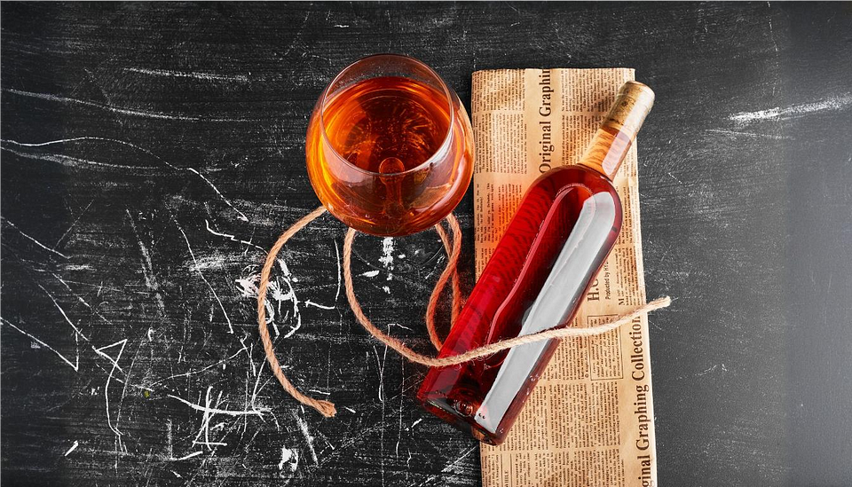 A bottle and glass of rose wine on a vintage newspaper. A bottle and glass of rose wine on a vintage newspaper.