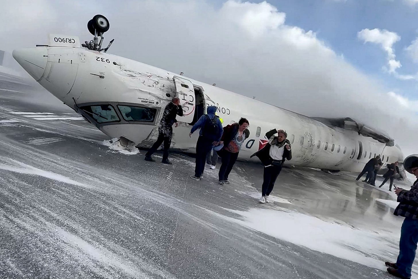Passengers leave a Delta Air Lines CRJ-900 jet after it crashed on landing at Toronto Pearson International Airport