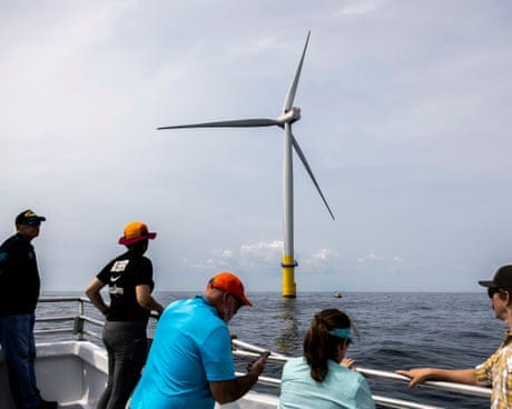 people look at a wind turbine sticking out of the water people look at a wind turbine sticking out of the water