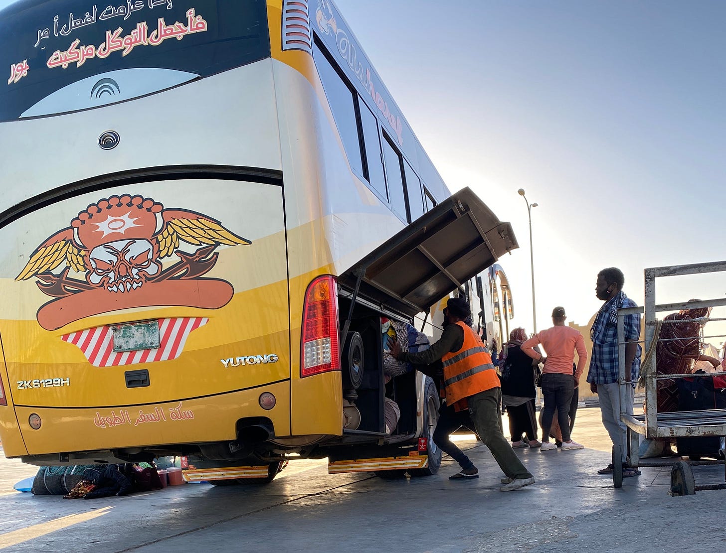 People are loading luggage into an already packed bus.