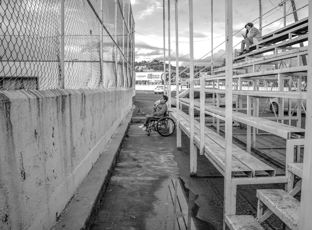 Person in wheelchair at a sporting event unable to see over concrete fence Person in wheelchair at a sporting event unable to see over concrete fence