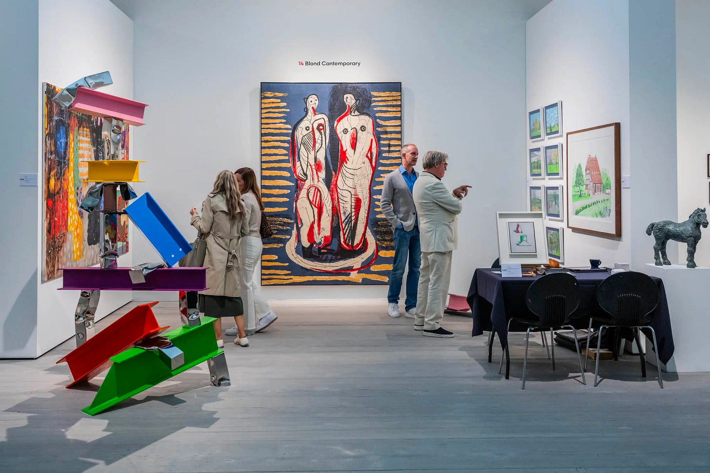 Visitors explore a gallery at the British Art Fair 2025, surrounded by colorful abstract sculptures and modern paintings on display.